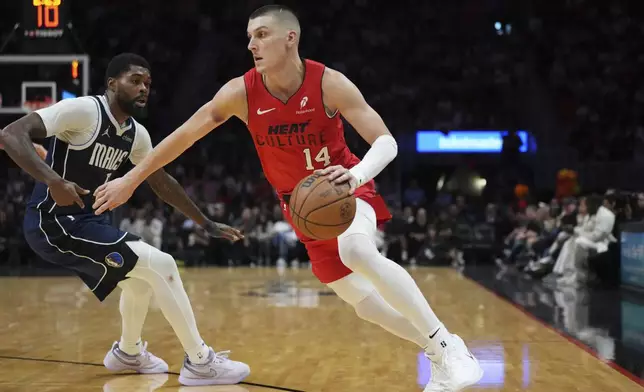 Miami Heat guard Tyler Herro (14) drives to the basket as Dallas Mavericks forward Naji Marshall (13) defends during the second half of an NBA basketball game, Sunday, Nov. 24, 2024, in Miami. (AP Photo/Jim Rassol)