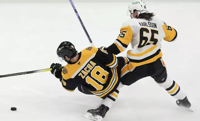 Pittsburgh Penguins' Erik Karlsson (65) and Boston Bruins' Pavel Zacha (18) battle for the puck during the first period of an NHL hockey game, Friday, Nov. 29, 2024, in Boston. (AP Photo/Michael Dwyer)