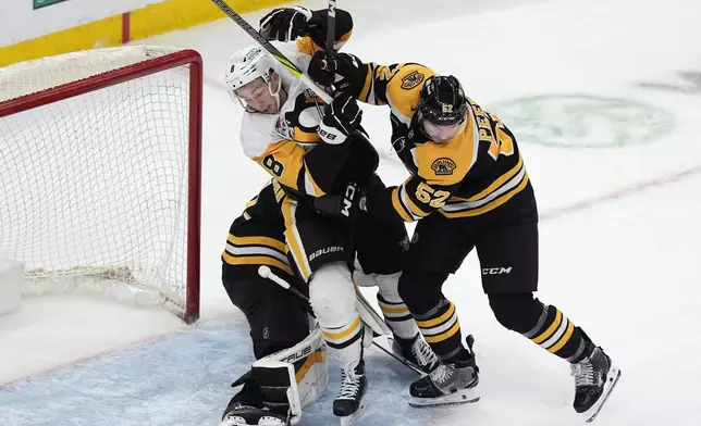 Boston Bruins' Andrew Peeke (52) checks Pittsburgh Penguins' Michael Bunting (8) during the first period of an NHL hockey game, Friday, Nov. 29, 2024, in Boston. (AP Photo/Michael Dwyer)