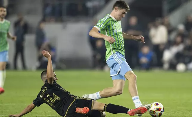 Seattle Sounders midfielder Reed Baker-Whiting, right, dribbles the ball over the tackle by Los Angeles FC defender Sergi Palencia (14) during the second half of an MLS Western Conference semifinal soccer match in Los Angeles, Saturday, Nov. 23, 2024. (AP Photo/Kyusung Gong)