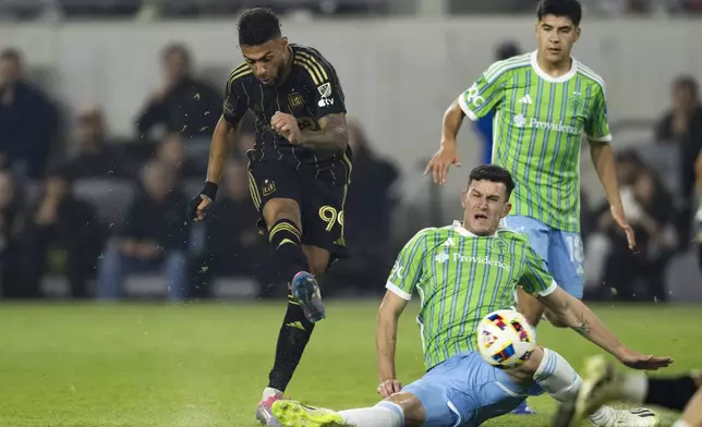 Los Angeles FC forward Denis Bouanga (99) shoots over the tackle by Seattle Sounders defender Nathan (4) during the second half of an MLS Western Conference semifinal soccer match in Los Angeles, Saturday, Nov. 23, 2024. (AP Photo/Kyusung Gong)