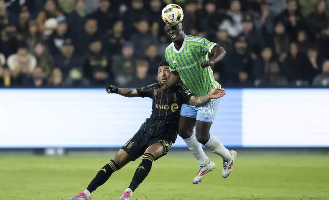 Seattle Sounders defender Yeimar Gómez (28) heads over Los Angeles FC forward Denis Bouanga (99) during the first half of an MLS Western Conference semifinal soccer match in Los Angeles, Saturday, Nov. 23, 2024. (AP Photo/Kyusung Gong)