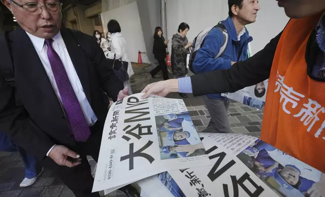 A staff member distributes an extra edition of the Yomiuri Shimbun newspaper reporting that Los Angeles Dodgers' Shohei Ohtani won his third Most Valuable Player award, Friday, Nov. 22, 2024, in Tokyo. (AP Photo/Eugene Hoshiko)