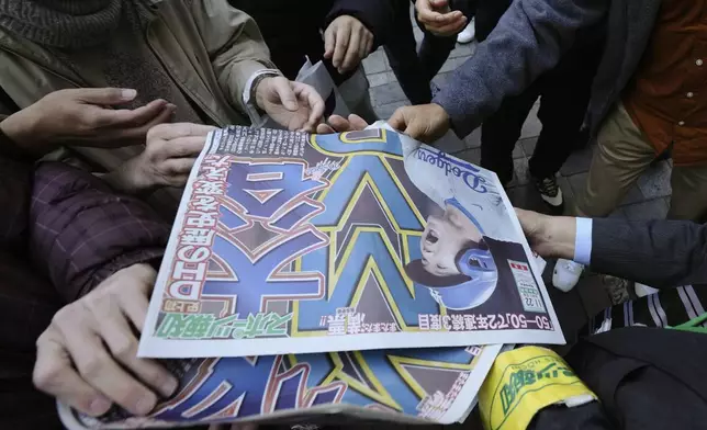 A staff member distributes an extra edition of the Sports Hochi newspaper reporting that Los Angeles Dodgers' Shohei Ohtani won his third Most Valuable Player award, Friday, Nov. 22, 2024, in Tokyo. (AP Photo/Eugene Hoshiko)