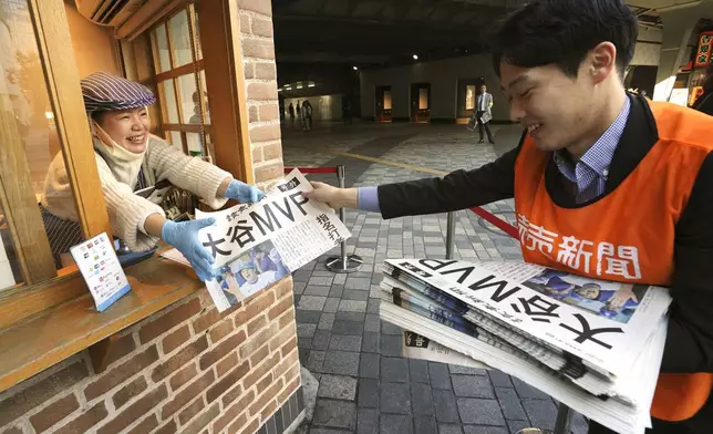 A staff member distributes an extra edition of the Yomiuri Shimbun newspaper reporting that Los Angeles Dodgers' Shohei Ohtani won his third Most Valuable Player award, Friday, Nov. 22, 2024, in Tokyo. (AP Photo/Eugene Hoshiko)