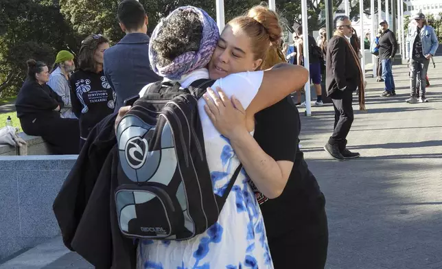 ADDS NAME - Jazmine Te Hiwi, right, embraces a friend as they arrive at Parliament House in Wellington, New Zealand ahead of the apology to the survivors of abuse in state, faith-based and foster care over a period of seven decades, Tuesday, Nov. 12, 2024. (AP Photo/Charlotte Graham-McLay )