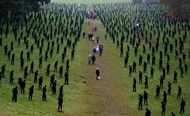 Visitors walk through the large-scale art installation, representing 1,475 silhouettes of Second World War military personnel, at Grecian Valley near Buckingham, England, Friday, Nov. 8, 2024. (AP Photo/Frank Augstein)