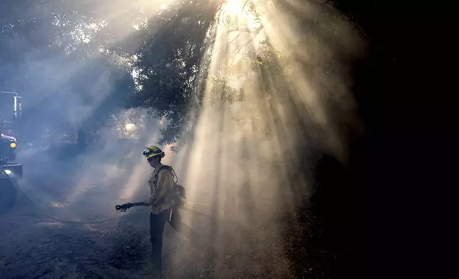 A firefighter walks through smoke while battling the Mountain Fire on Thursday, Nov. 7, 2024, in Santa Paula, Calif. (AP Photo/Noah Berger)