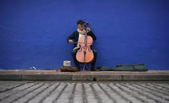 Fabio Guarin, 78, an amateur musician, plays the cello for tips in La Candelaria neighborhood of Bogota, Colombia, Friday, Nov. 8, 2024. (AP Photo/Fernando Vergara)