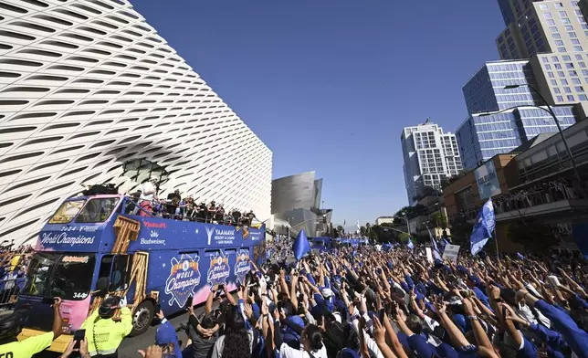 Fans wave at Los Angeles Dodgers coaches and players as they are driven past on buses during the team's baseball World Series championship parade Friday, Nov. 1, 2024, in Los Angeles. (AP Photo/Kyusung Gong)