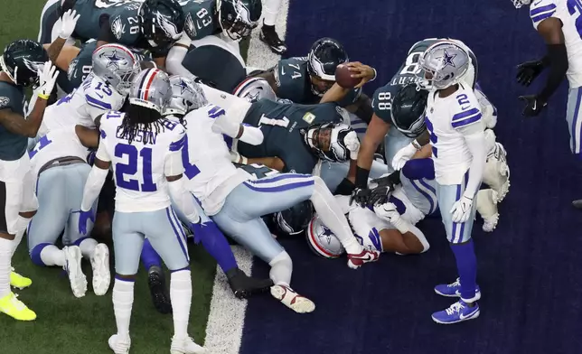 Philadelphia Eagles quarterback Jalen Hurts (1) lays out into the end zone to score a touchdown as Dallas Cowboys' Caelen Carson (21), Jourdan Lewis (2) and others defend in the first half of an NFL football game in Arlington, Texas, Sunday, Nov. 10, 2024. (AP Photo/Gareth Patterson)