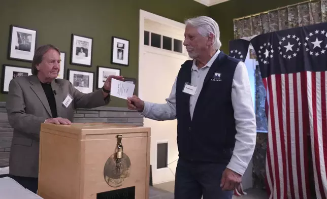 Town Moderator Tom Tillotson, left, accepts the first ballot from Les Otten during the midnight vote on Election Day, Tuesday, Nov. 5, 2024, in Dixville Notch, N.H. (AP Photo/Charles Krupa)