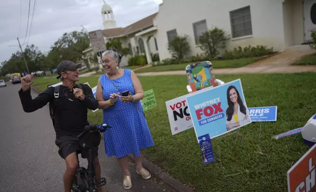 Trump supporter Barney Morin, left, cheers as Democratic poll greeter Lynn Akin helps him find his polling place so he can vote, outside a voting bureau at First United Methodist Church on Election Day, Tuesday, Nov. 5, 2024, in Gulfport, Fla. (AP Photo/Rebecca Blackwell)