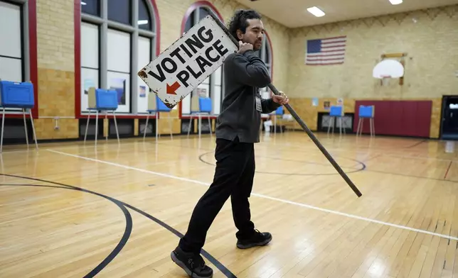 Election day worker Sean Vander Waal prepares to open a polling place,Tuesday, Nov. 5, 2024, in Dearborn, Mich. (AP Photo/Charlie Neibergall)