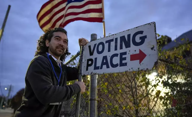 Election day worker Sean Vander Waal prepares to open a polling place,Tuesday, Nov. 5, 2024, in Dearborn, Mich. (AP Photo/Charlie Neibergall)