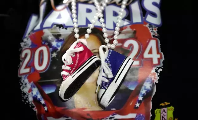 A supporter wears decorative Converse sneakers on a necklace as Democratic presidential nominee Vice President Kamala Harris speaks at a campaign rally at Jenison Field House on the campus of Michigan State University, Sunday, Nov. 3, 2024, in East Lansing, Mich. (AP Photo/Jacquelyn Martin)