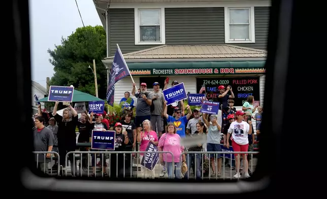 Supporters of Republican presidential candidate former President Donald Trump look on as a bus carrying Democratic presidential nominee Vice President Kamala Harris passes by following a campaign event, Sunday, Aug. 18, 2024, in Rochester, Pa. (AP Photo/Julia Nikhinson)