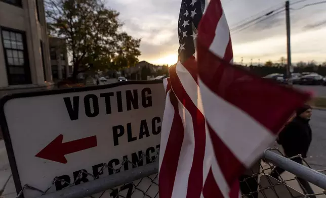 An American flag flies in the wind as a voter leaves a polling site after casting a ballot on Election Day, Tuesday, Nov. 5, 2024, in Dearborn, Mich. (AP Photo/David Goldman)