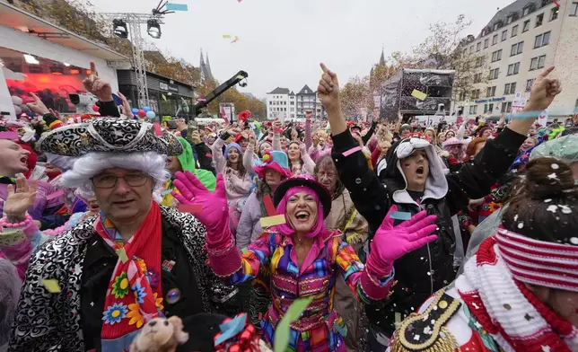 Costumed revelers celebrate at the central Heumarkt while tens of thousands of carnival fools take to the streets of Cologne, Germany, Monday, November 11, 2024, heralding the official start of the carnival season. (AP Photo/Martin Meissner)