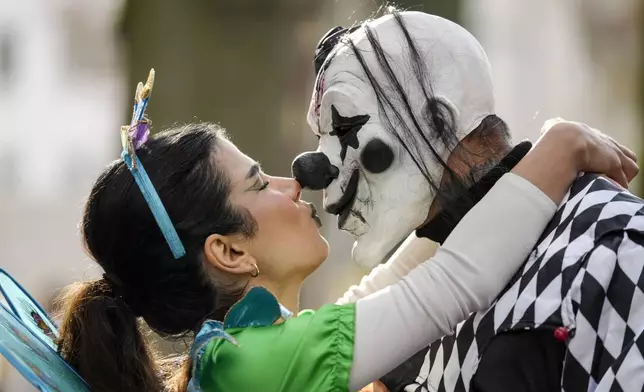 Revelers dressed in costumes kiss at the Zuelpicher Street while tens of thousands of carnival fools take to the streets of Cologne, Germany, on Monday, Nov. 11, 2024, heralding the official start of the carnival season. (AP Photo/Martin Meissner)