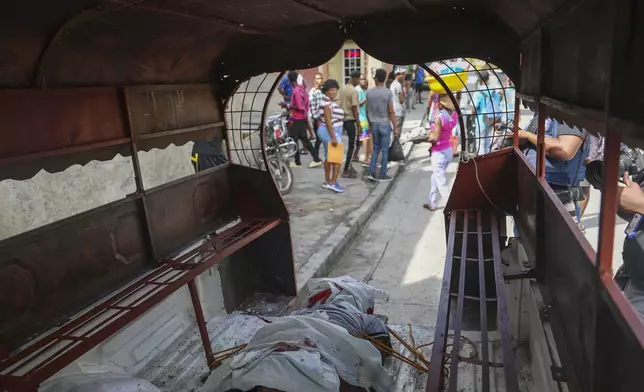 The body of a man who was shot dead by a stray bullet, is secured to the floor of a tap-tap, in the Solino neighborhood of Port-au-Prince, Haiti, Tuesday, Nov. 12, 2024. (AP Photo/Odelyn Joseph)