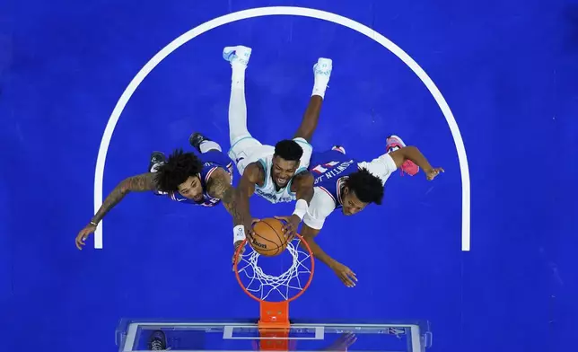 Charlotte Hornets' Brandon Miller, center, dunks between Philadelphia 76ers' Kelly Oubre Jr., left, and Jeff Dowtin Jr. during the second half of an NBA basketball game, Sunday, Nov. 10, 2024, in Philadelphia. (AP Photo/Matt Slocum)