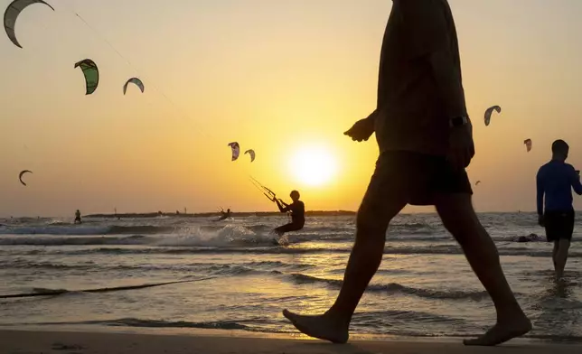 A kite surfer is silhouetted during a surfing session on the Mediterranean sea, in Tel Aviv, Israel, Wednesday, Nov. 6, 2024. (AP Photo/Francisco Seco)