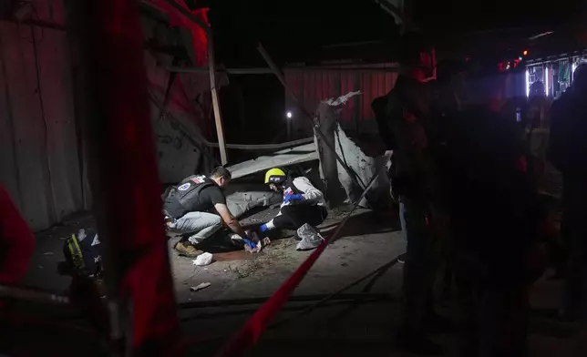 Members of ZAKA rescue services clean the blood stains at the site where a rocket fired from Lebanon hit a storage facility in the northern Israeli town of Nahariya, killing two people on Tuesday, Nov. 12, 2024. (AP Photo/Francisco Seco)