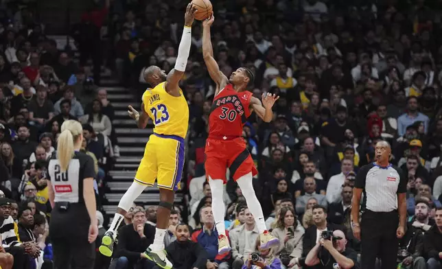 Los Angeles Lakers' LeBron James (23) and Toronto Raptors' Ochai Agbaji (30) battle for the ball during the first half of an NBA basketball game in Toronto on Friday, Nov. 1, 2024. (Frank Gunn/The Canadian Press via AP)