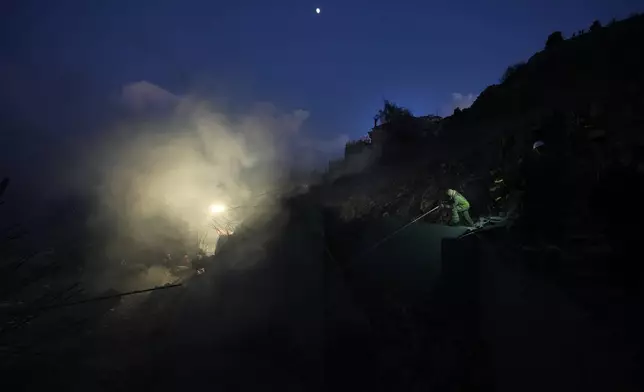 A firefighter, right, extinguishes a fire as smoke rises from a house hit in an Israeli airstrike in Baalchmay village east of Beirut, Lebanon, Tuesday, Nov. 12, 2024. (AP Photo/Hassan Ammar)