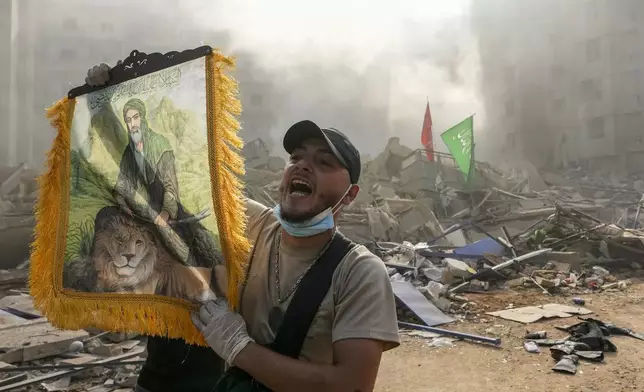 A man shouts slogans as he holds a picture depicting Imam Ali at the site of an Israeli airstrike in Dahiyeh, Beirut, Lebanon, Friday, Nov. 1, 2024. (AP Photo/Hassan Ammar)