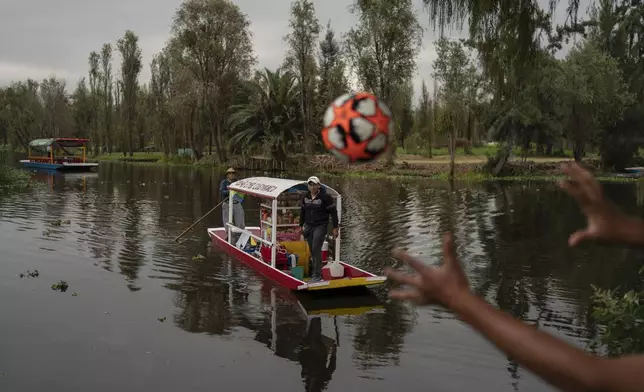 A man on a traditional canoe launches a soccer ball that fell into the lake in the Xochimilco borough of Mexico City, Sunday, Oct. 20, 2024. (AP Photo/Felix Marquez)