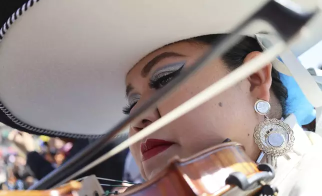 Daniela Orgin, plays her violin before a gathering to break the record of most mariachis performing in unison, at the Zocalo, Mexico City's main square, Sunday, Nov. 10, 2024. (AP Photo/Ginnette Riquelme)