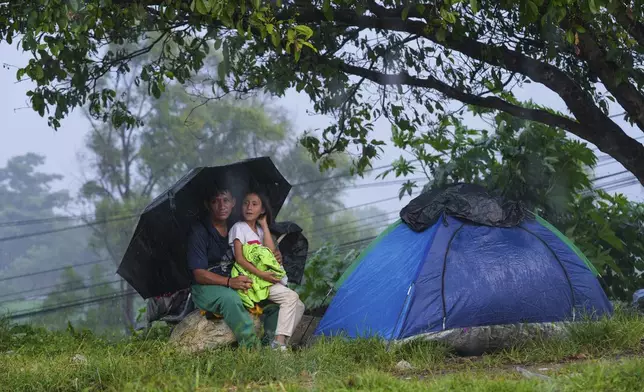 Migrants take cover from the rain after arriving at a makeshift shelter in Huixtla, Chiapas state, Mexico, Wednesday, Nov. 6, 2024, hoping to reach the country's northern border and ultimately the United States. (AP Photo/Moises Castillo)