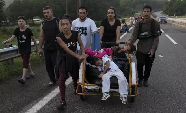 Migrants walk along the Huixtla highway hoping to reach the country's northern border and ultimately the United States, in Huehuetan, southern Mexico, Wednesday, Nov. 6, 2024. (AP Photo/Moises Castillo)