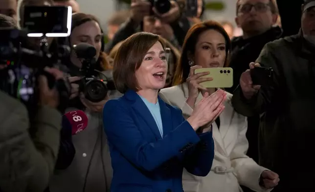 Moldova's President Maia Sandu claps her hands next to media as preliminary results are announced for the presidential election runoff in Chisinau, Moldova, Sunday, Nov. 3, 2024. (AP Photo/Vadim Ghirda)