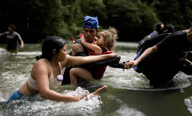 Venezuelan migrant Alvaro Calderini carries his niece across a river near Bajo Chiquito, Panama, after walking across the Darien Gap from Colombia on their way north to the United States, Saturday, Nov. 9, 2024. (AP Photo/Matias Delacroix)