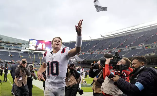 New England Patriots quarterback Drake Maye tosses a fan a souvenir from the team's 19-3 win over the Chicago Bears in an NFL football game Sunday, Nov. 10, 2024, in Chicago. (AP Photo/Erin Hooley)