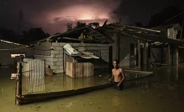 A resident wades through a flooded street caused by heavy rains from typhoon Toraji in Ilagan City, Isabela province, northern Philippines on Tuesday, Nov. 12, 2024. (AP Photo/Noel Celis)