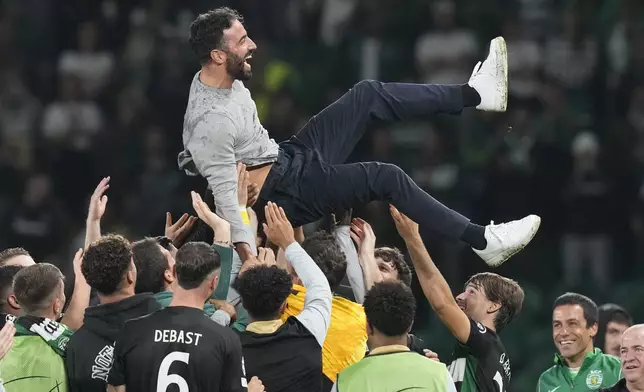 Sporting players toss coach Ruben Amorim into the air during the UEFA Champions League opening phase soccer match between Sporting and Manchester City in Lisbon, Portugal, Tuesday, Nov. 5, 2024. (AP Photo/Armando Franca)