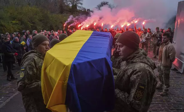 An honor guard carries the coffin of fallen Ukrainian serviceman of 3rd assault brigade Danylo Liashkevych, known as "Berserk", who was killed together with his girlfriend Valentyna Nagorna, known as "Valkiria", during the funeral ceremony at a crematorium in Kyiv, Ukraine, Friday Nov. 8, 2024. (AP Photo/Evgeniy Maloletka)