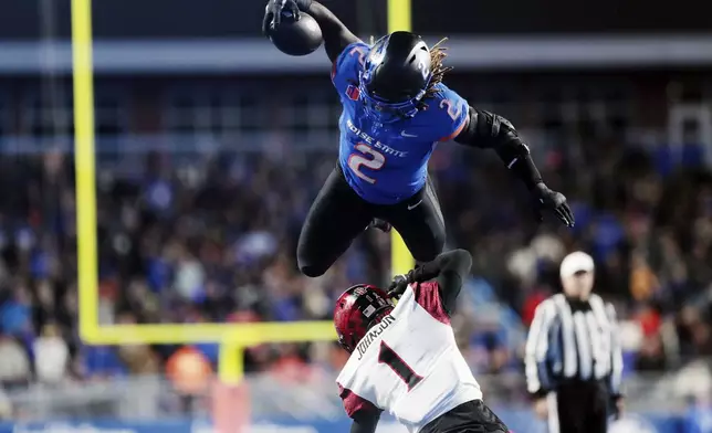 Boise State running back Ashton Jeanty leaps over San Diego State cornerback Chris Johnson during the second half of an NCAA college football game Friday, Nov. 1, 2024, in Boise, Idaho. (Kyle Green/Idaho Statesman via AP)