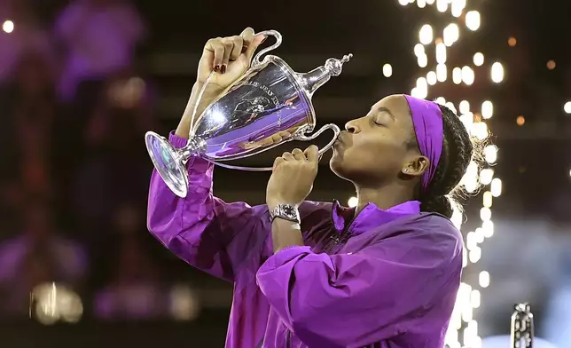 Coco Gauff of the U.S. kisses her trophy after winning against China's Qinwen Zheng in their women's singles final match of the WTA finals at the King Saud University Indoor Arena, in Riyadh, Saudi Arabia, Saturday, Nov. 9, 2024. (AP Photo)