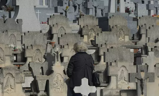 A woman stands in front of a grave in the Almudena cemetery during All Saints Day, a Catholic holiday to reflect on the saints and deceased relatives, Madrid, Spain, Friday, Nov. 1, 2024. (AP Photo/Paul White)