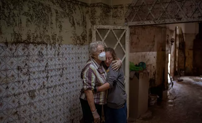 Vero Almarche, 36, right, hugs her neighbor Maria Munoz, 74, who was born in the house where they are photographed and which was destroyed by flooding in Masanasa, Valencia, Spain, Wednesday, Nov. 6, 2024. (AP Photo/Emilio Morenatti)