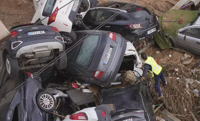 A civil guard searches for survivors in cars piled up on the outskirts of Valencia, Spain, Friday, Nov. 1, 2024 after flooding. (AP Photo/Alberto Saiz)