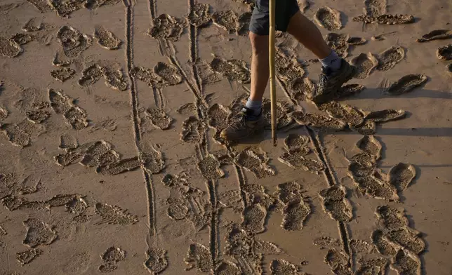 A man walks on a mud-covered road after flooding in Valencia, Spain, Thursday, Oct. 31, 2024. (AP Photo/Manu Fernandez)