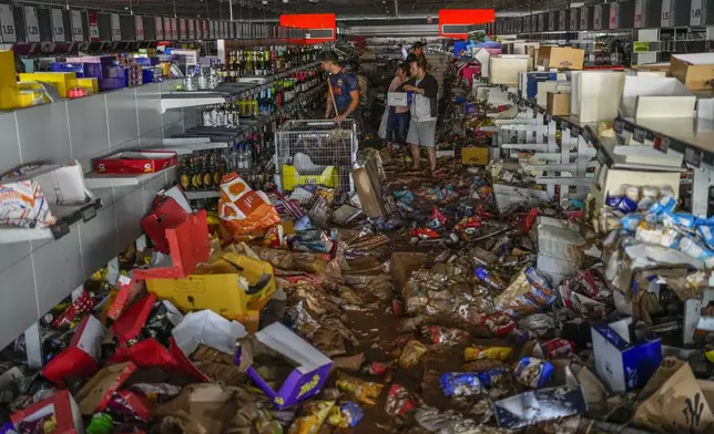 People pick up goods in a supermarket affected by the floods in Valencia, Spain, Thursday, Oct. 31, 2024. (AP Photo/Manu Fernandez)