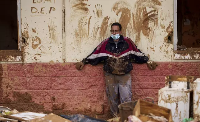 A man looks at the damage and debris in front of a house a affected by floods in Alfafar, Spain, on Monday, Nov. 4, 2024. (AP Photo/Manu Fernandez)