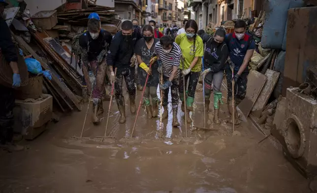 Volunteers and residents clean the mud from the streets in an area affected by floods in Paiporta, Valencia, Spain, Tuesday, Nov. 5, 2024. (AP Photo/Emilio Morenatti)